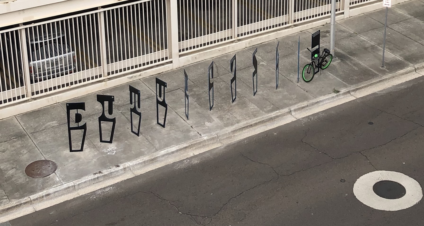 A row of bike racks with cutout letters visible at different angles reading DUUUVAL