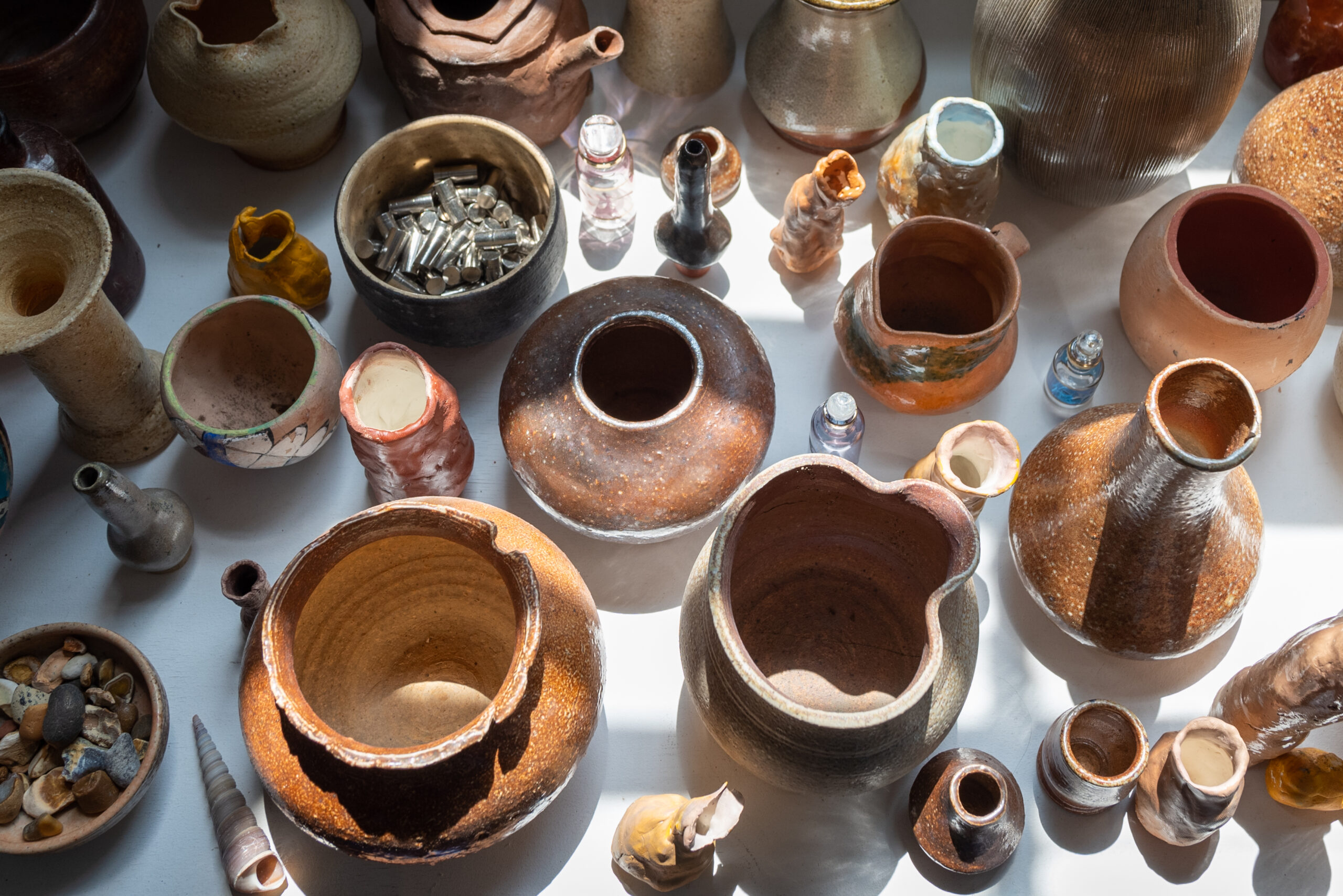 A collection of earth-colored clay vessels of various sizes viewed from above