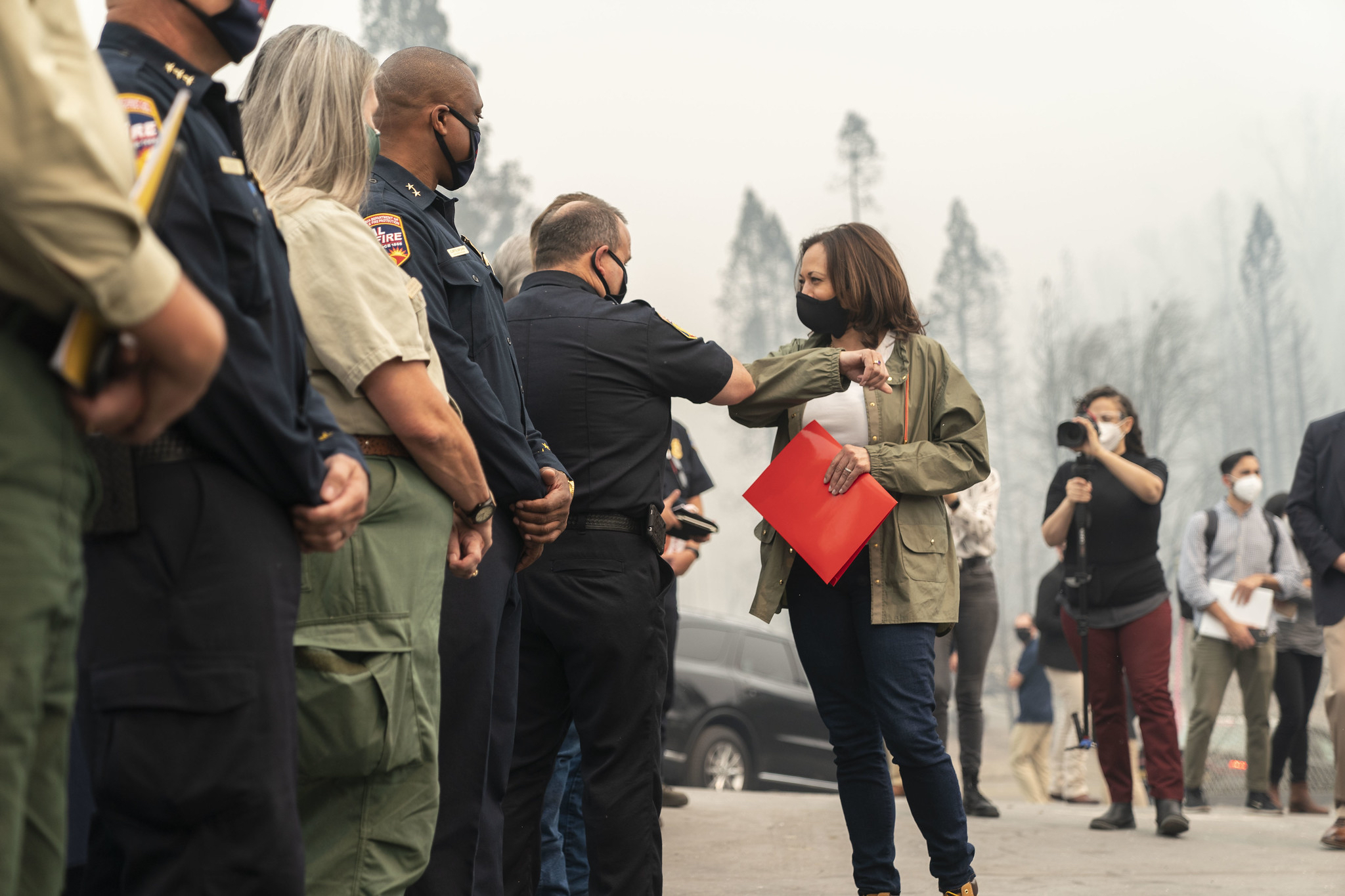 A masked Kamala Harris elbow bumps masked, uniformed people in a line as Nasreen Alkhateeb films behind them