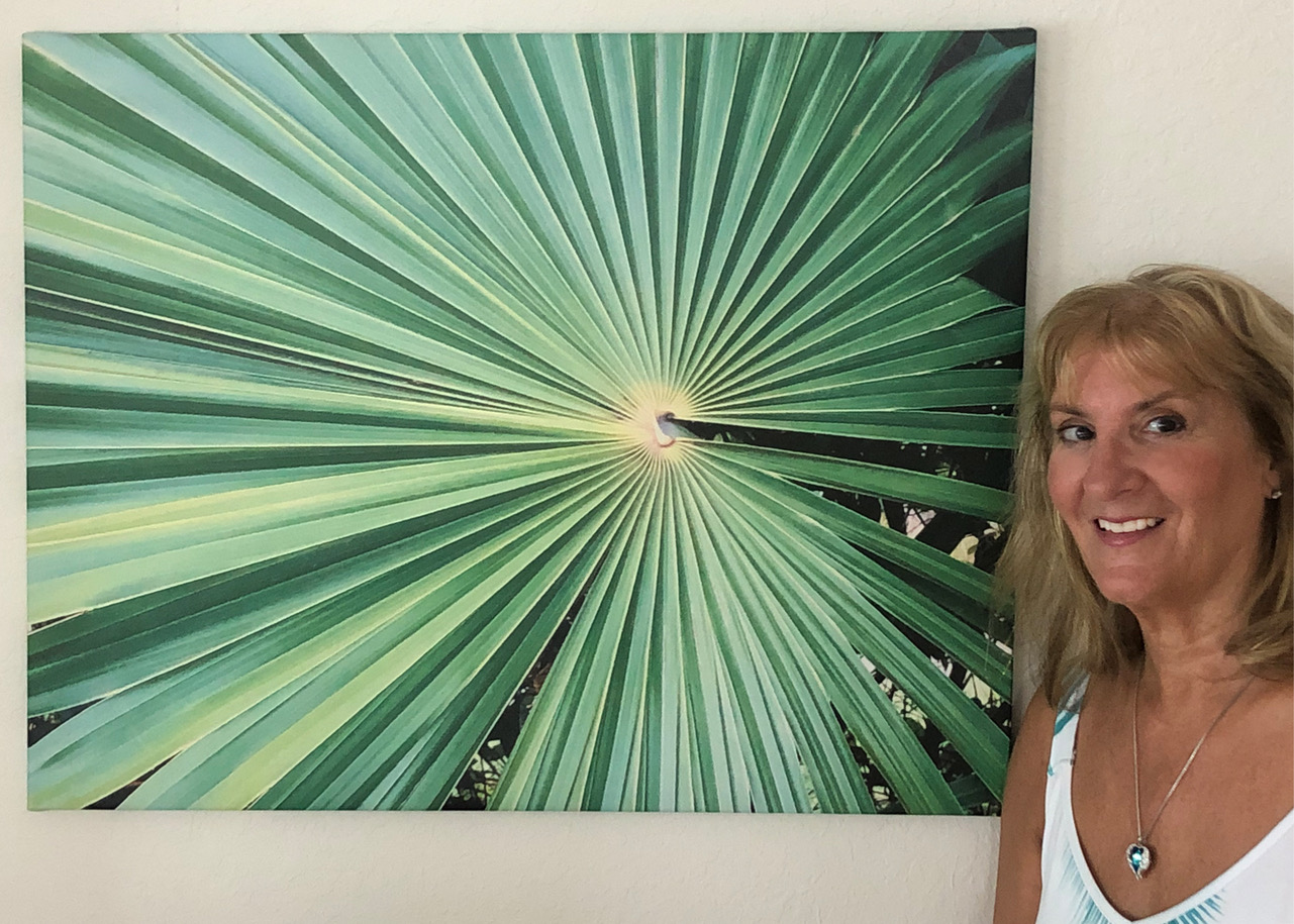 Person standing to the right of enlarged photograph of palm leaves.