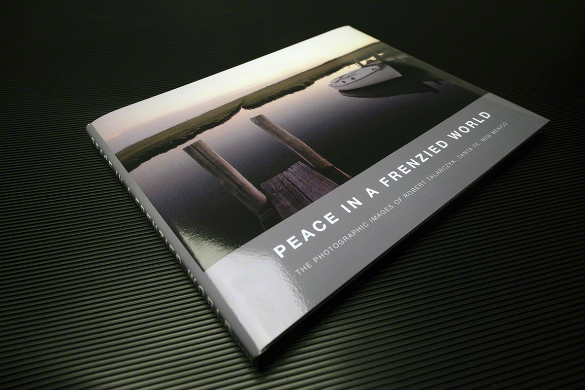 The book Peace in a Frenzied World, depicting a rustic wooden pier and still water on its cover, lays on a ridged surface