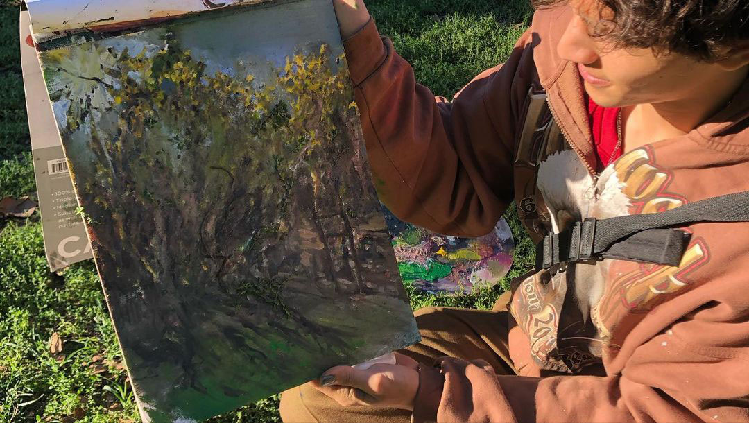 A person holding up their painting to show to the camera