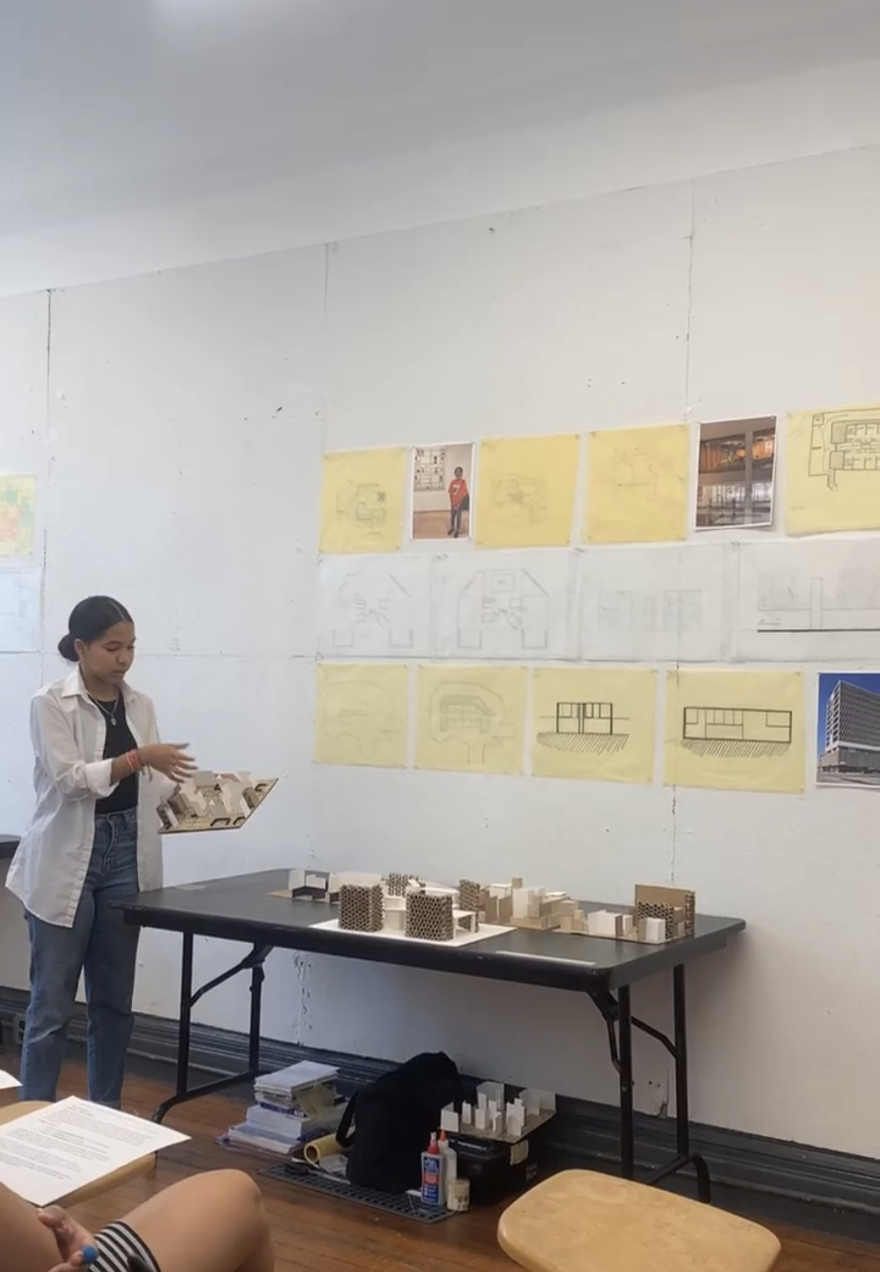 A person observing a cardboard model among other models on a table