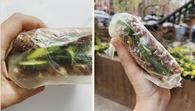 Hands holding a sandwich wrapped in clear film
