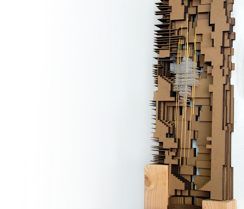 Architectural model resting on a wooden platform in front of a white wall.