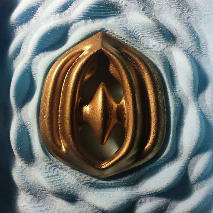 3D render of a morphological bronze object resting in undulating blue material. Vaguely resembles a flower.