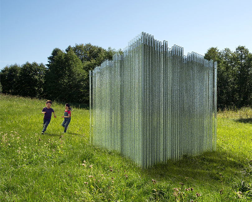 Render of two children in a grassy field running around a large glass cube.