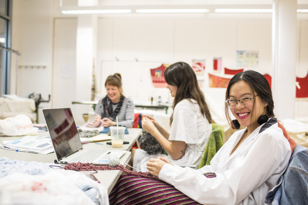 a group of students, working and conversing on laptops, in a pratt classroom