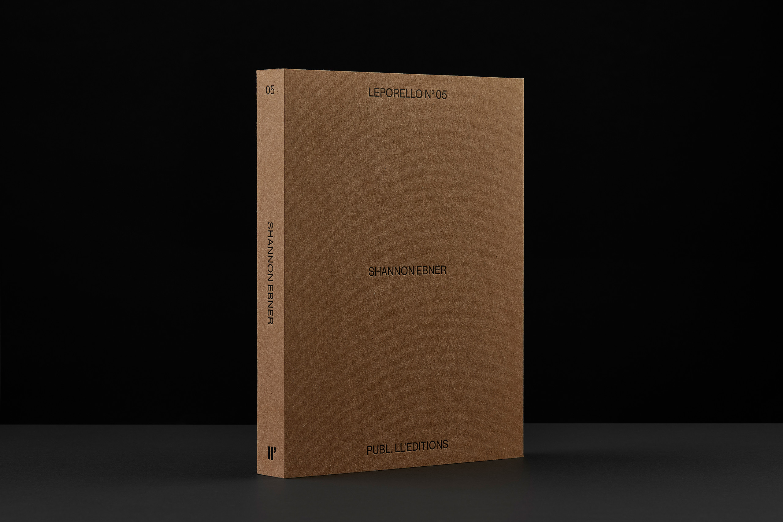Book with brown paper cover and embossed type placed before black background