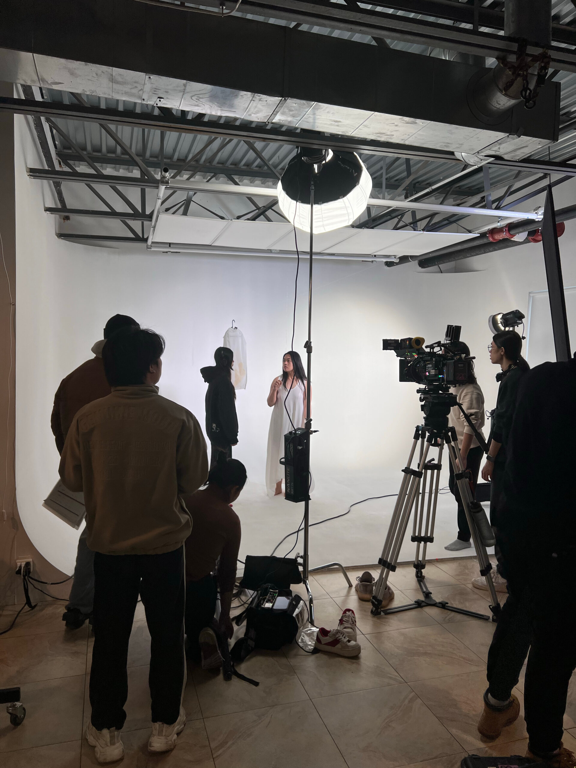a photo of a photoshoot. a student stands in front of a white background