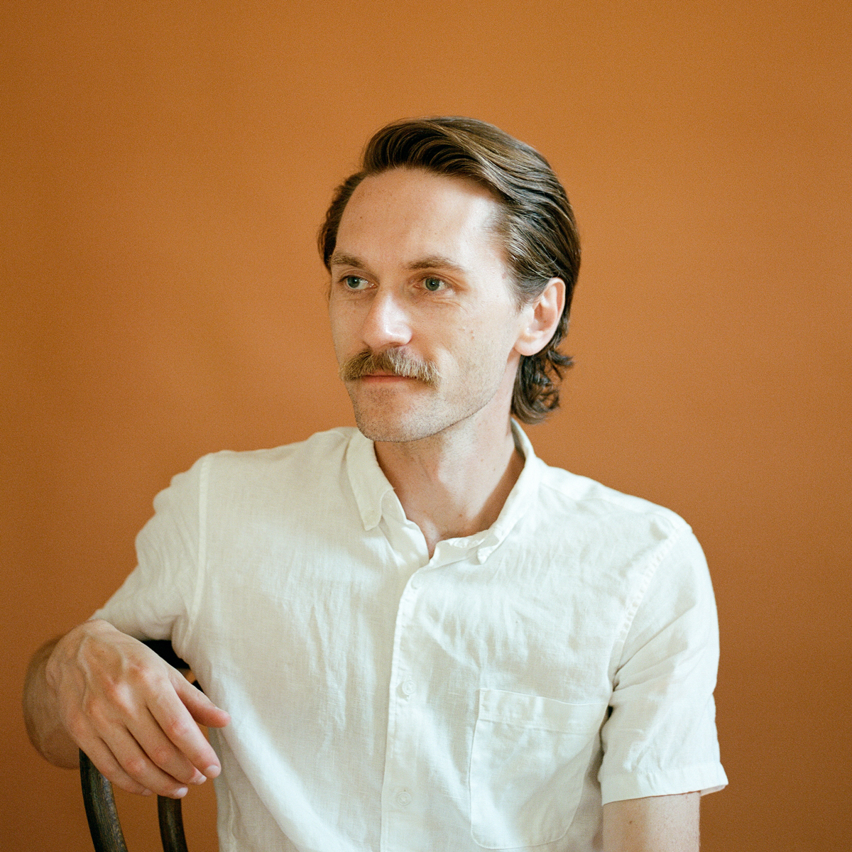 A photo of Alex wearing a white short sleeve button-down.