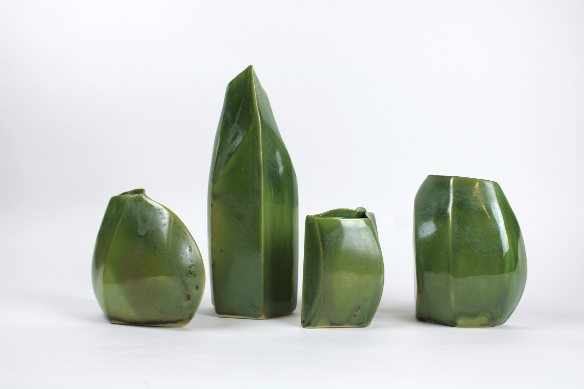 four green ceramic vases with organic forms