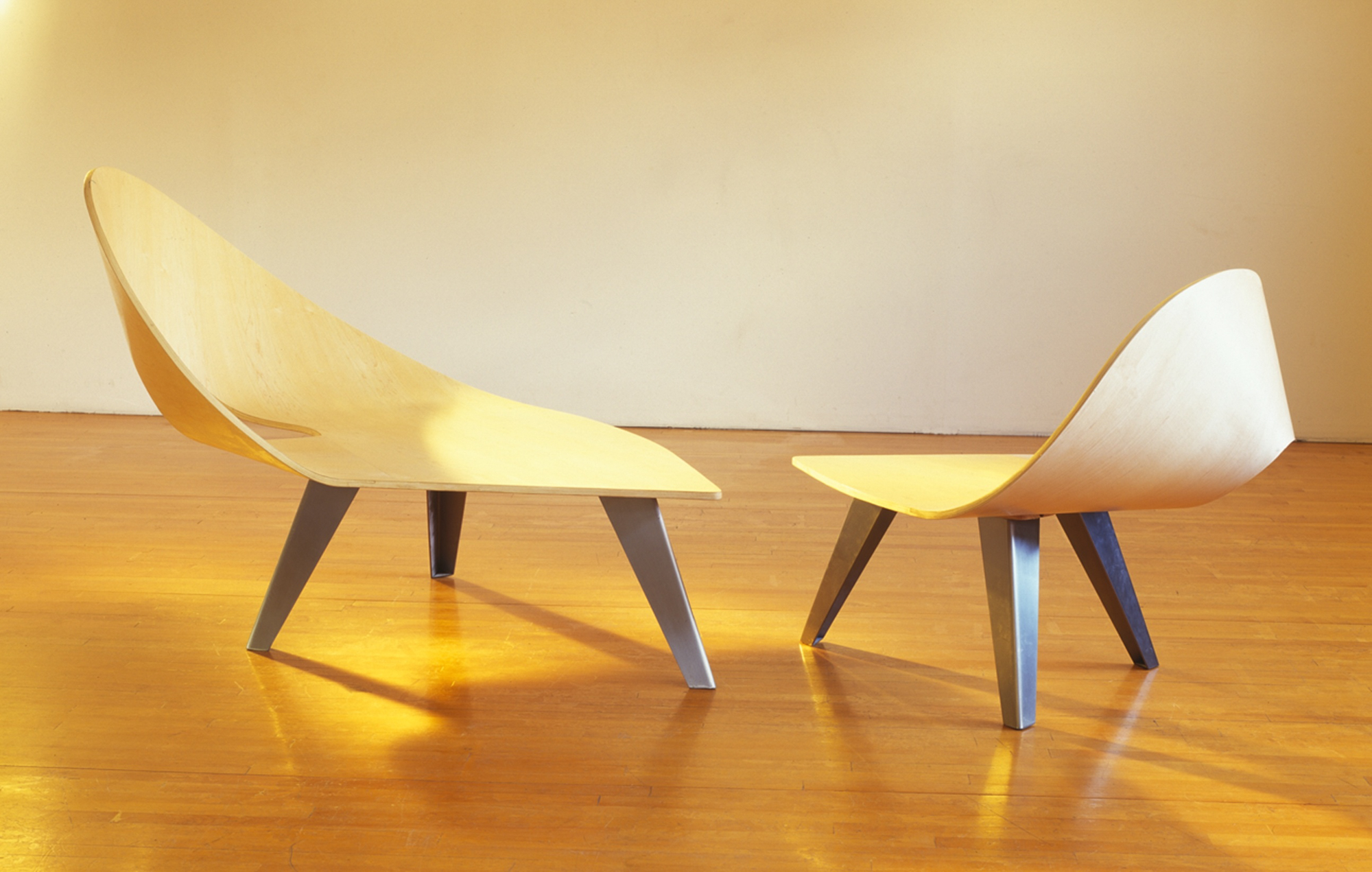 two bent plywood chairs with low tripod legs