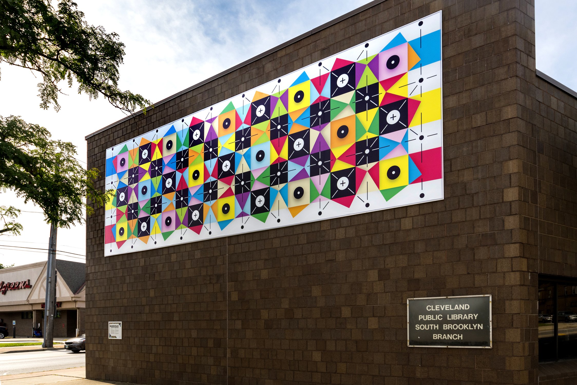 An abstract mural featuring squares, triangles, dots, and lines interlocking in various patterns and colors.