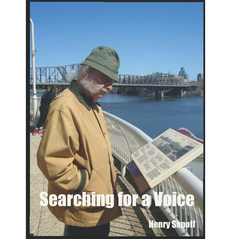 A photograph of the author in a rimmed hat and a coat, reading at a historically informative plaque by the water near a bridge.