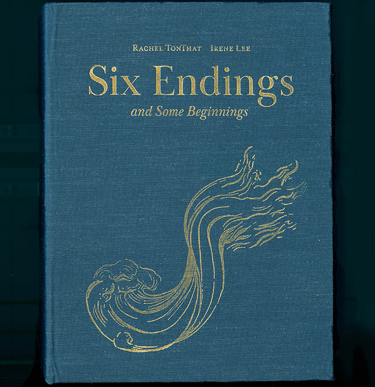 A blue clothbound book that features an illustration in gold. The left half of the illustration depicts a wave, but twists near the center, turning into a representation of flames in the right half.