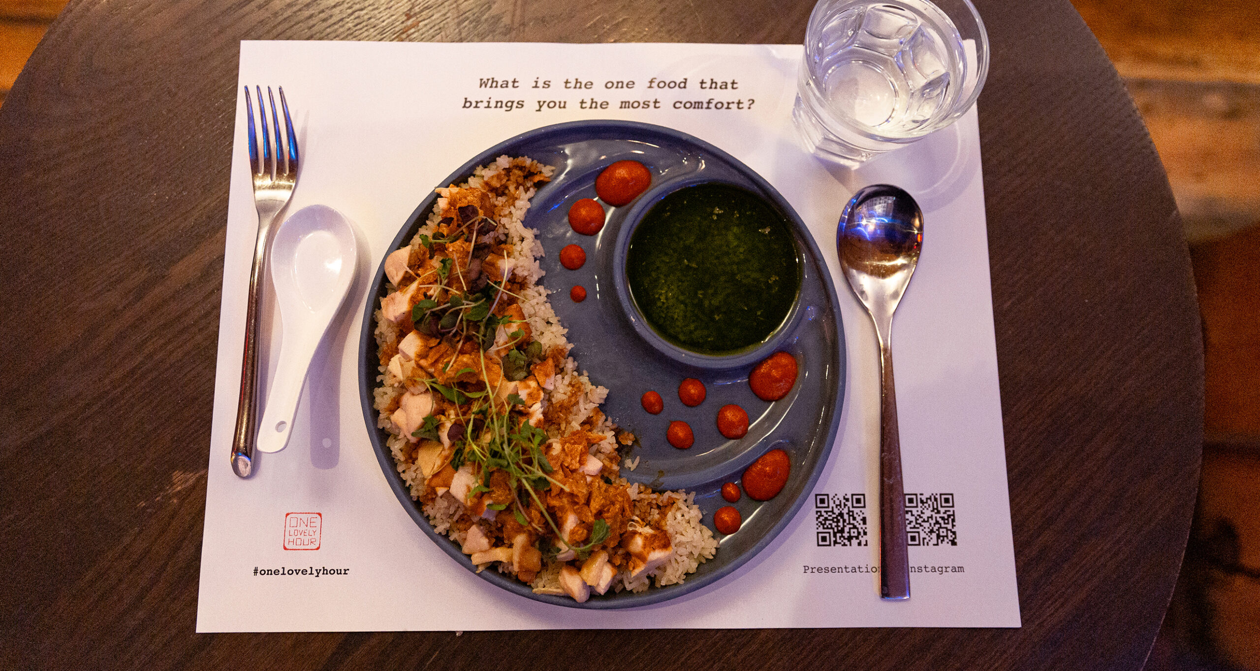 Gray bowl-plate with colorfully dressed rice dish on a placemat that reads What is the one food that brings you the most comfort?