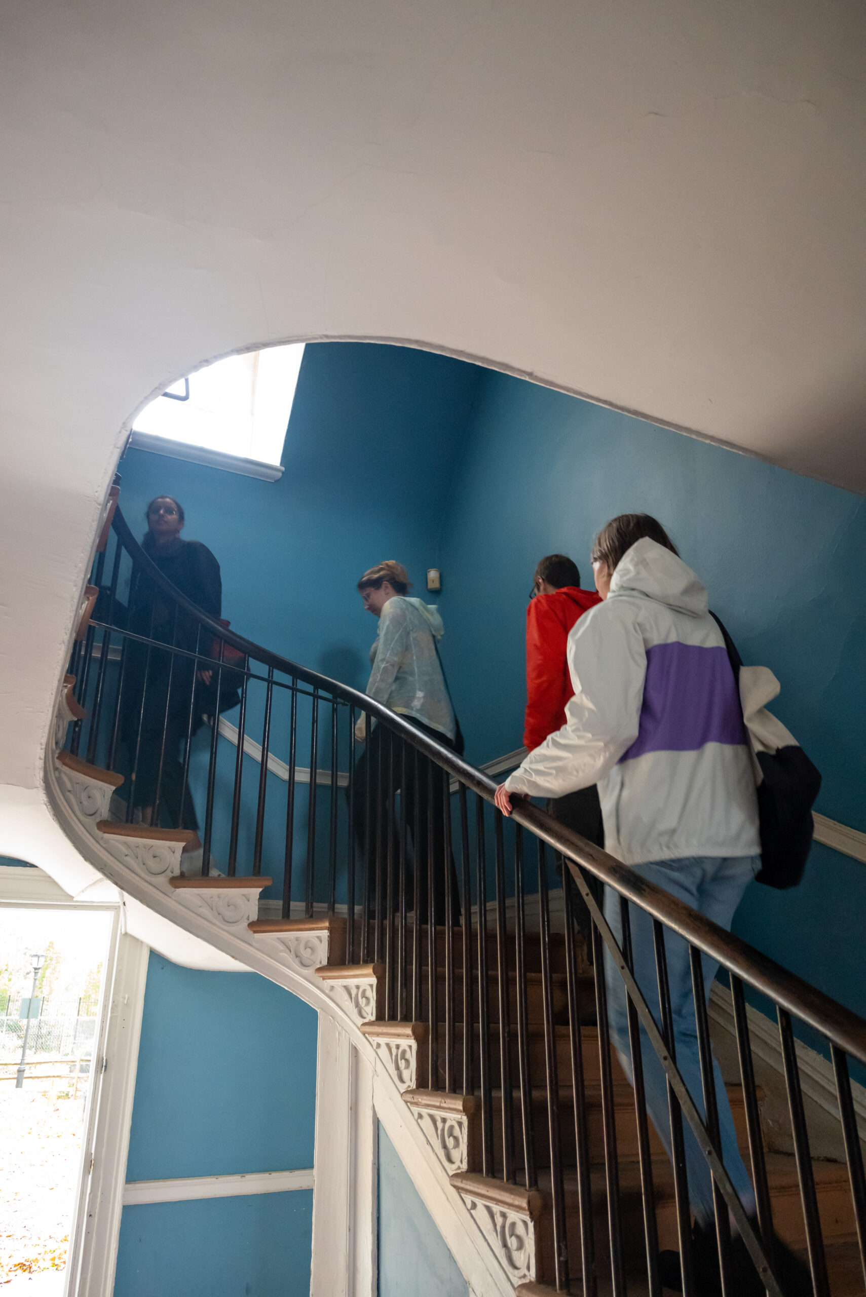 Students climb curved staircase of colonial house