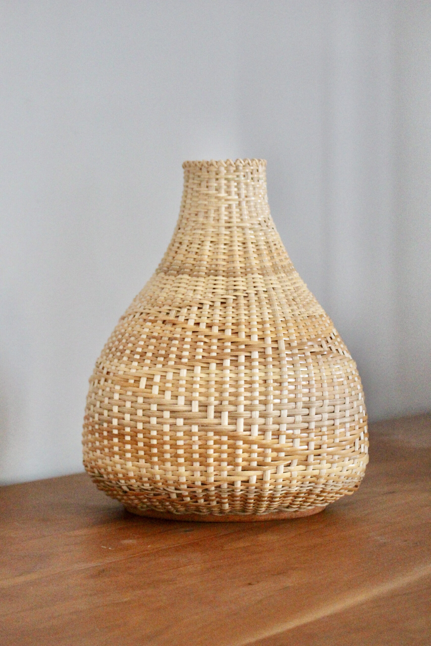 Woven vessel with wide base tapering in to a narrow opening at top