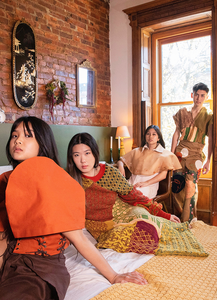 Four people model woven and sewn garments in an orange, ocher, red, and green color palette, some featuring repeating graphic motifs