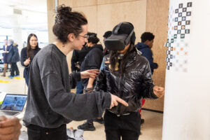 a student speaking with someone, a person in a vr headset in the background
