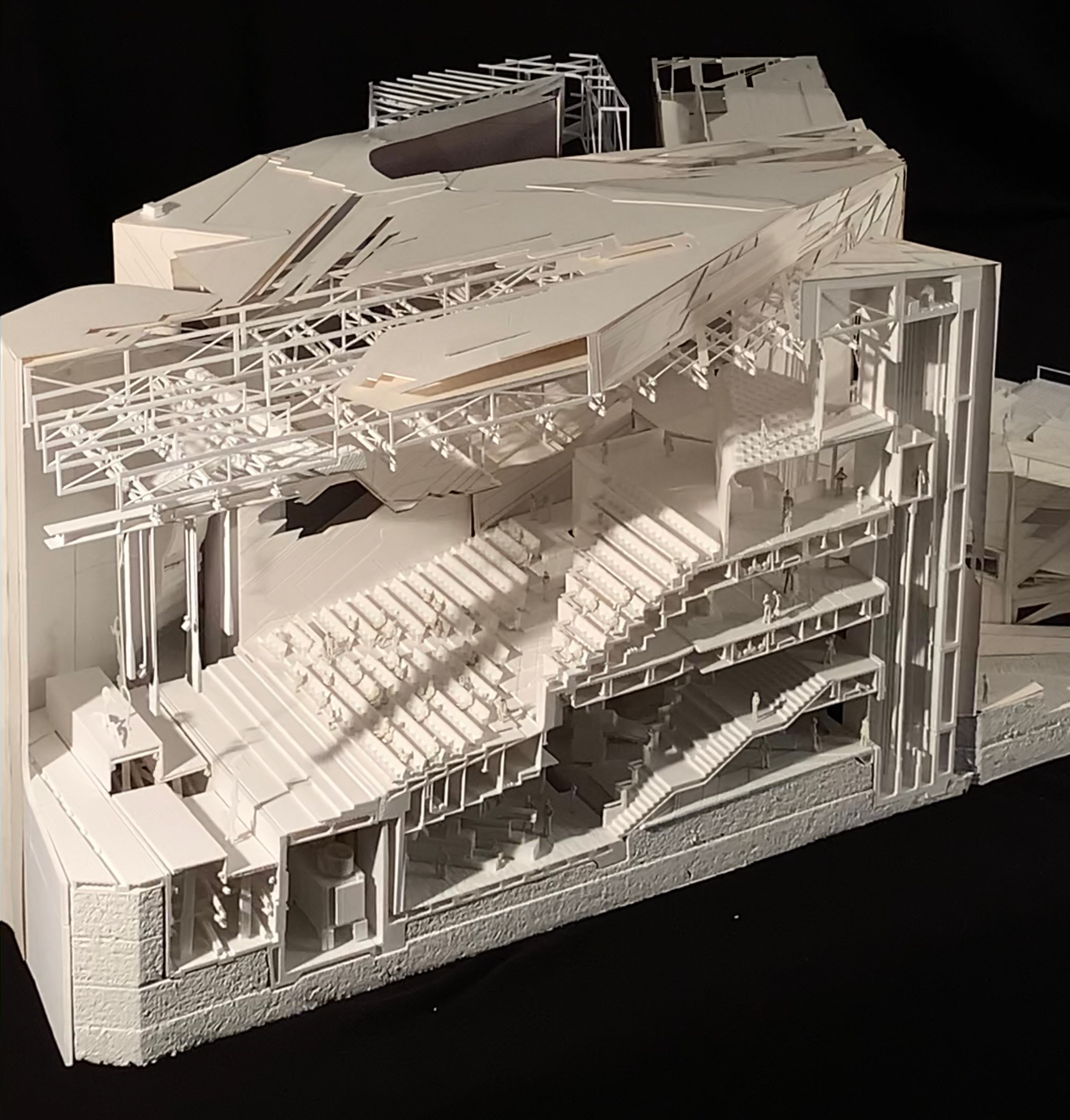 A white architectural model set on a black backdrop. The viewer can see a cross section of what appears to be a performance hall.