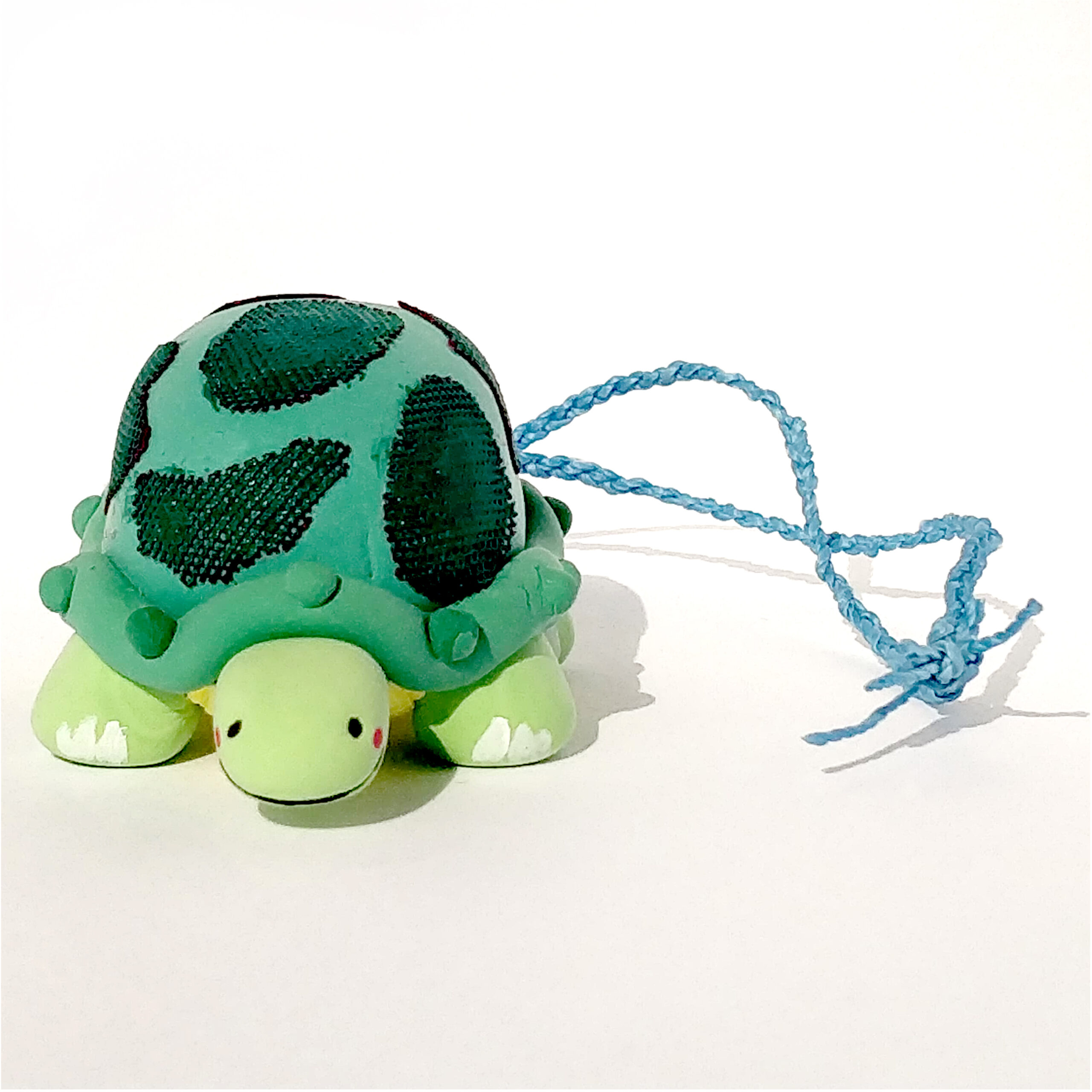 A photo of a plush turtle on a braided strap.