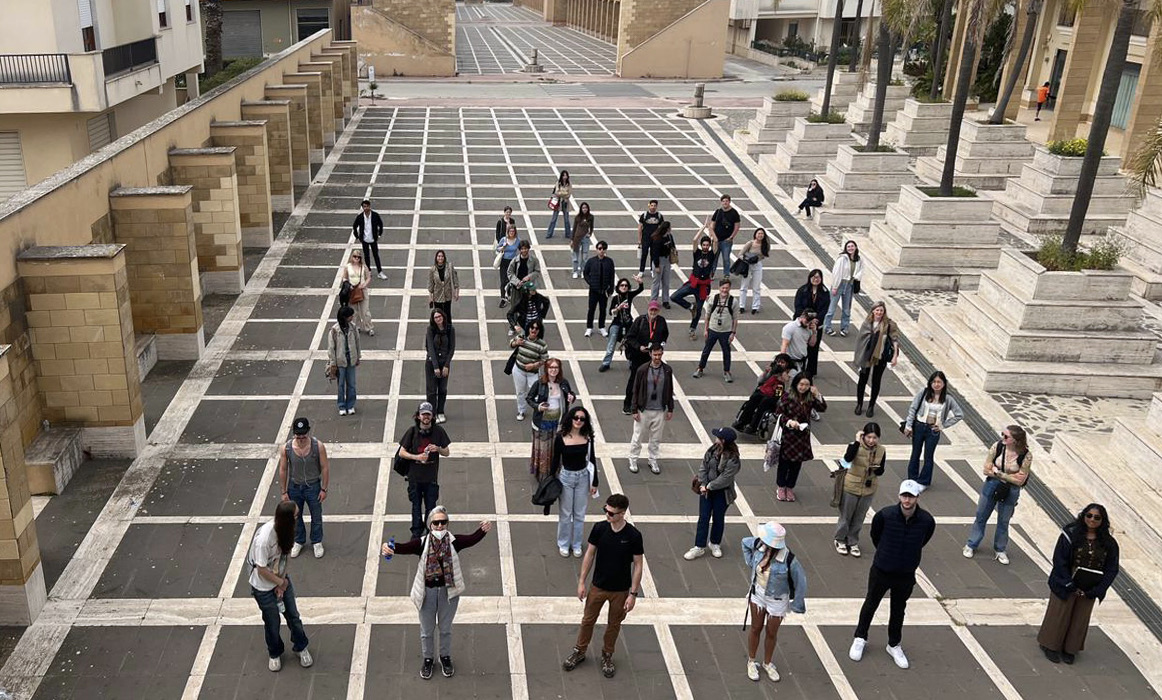 Image of a stree in Rome. Pedestrians are walking along marbled floors.