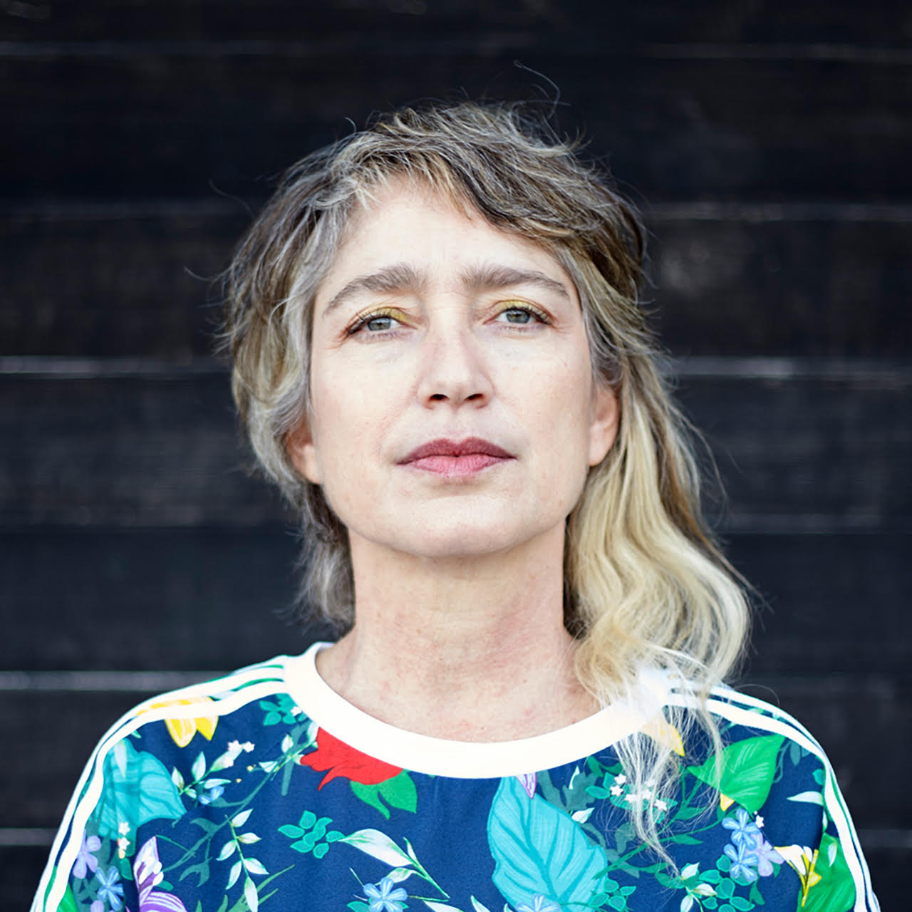 Headshot of Eva Davidova. She is looking sternly at the camera and there is a brick background.