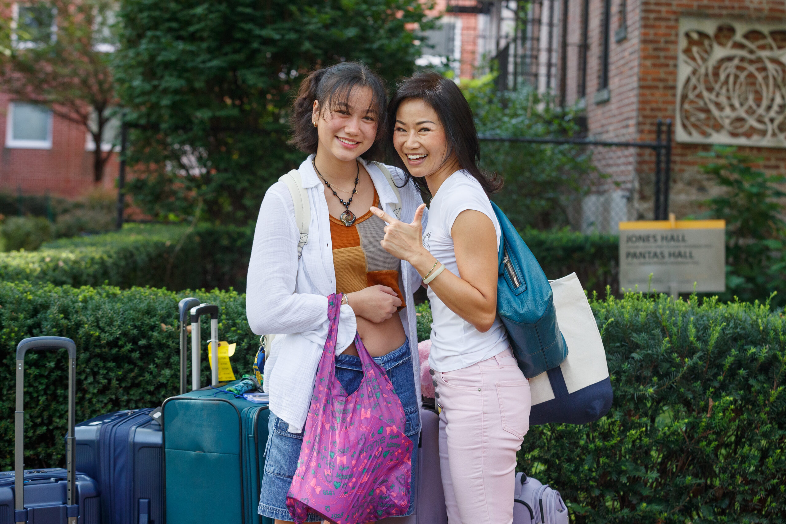 two people, smiling, standing, with campus in the background
