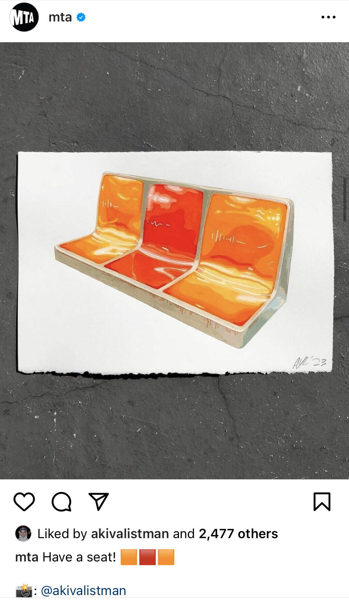 An Instagram post by MTA of a photograph of a painting of red and orange subway seats on a white sheet of paper lying a gray surface. The caption of the post reads “Have a seat!”