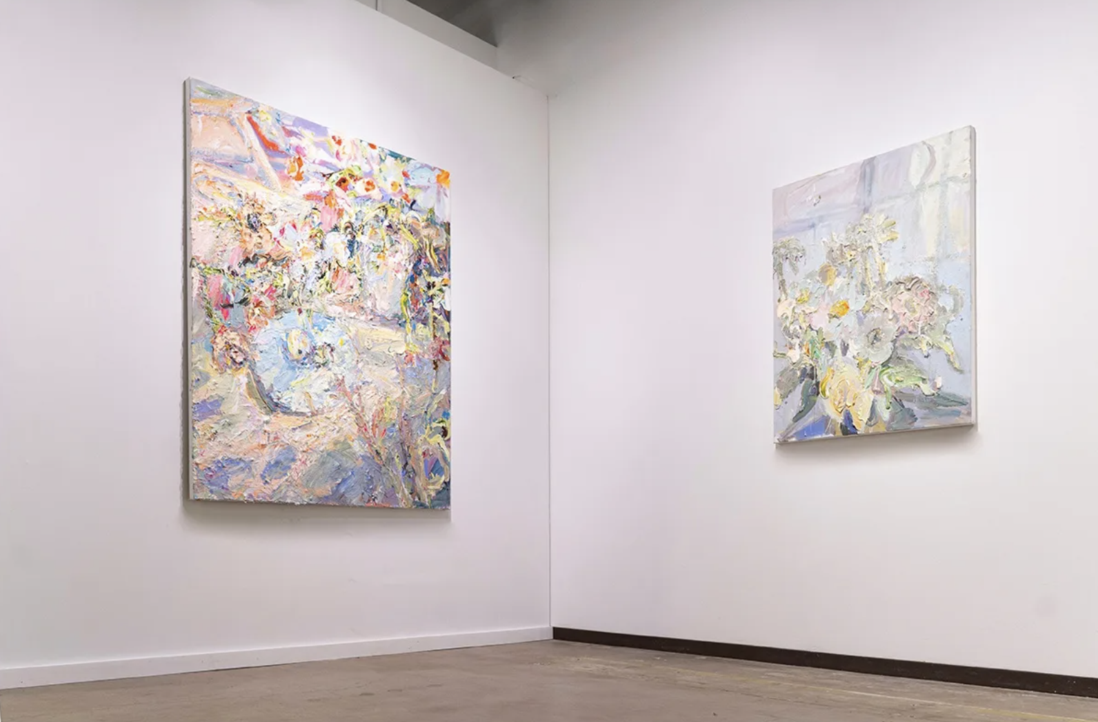 A photograph of two abstract paintings in a white art gallery.