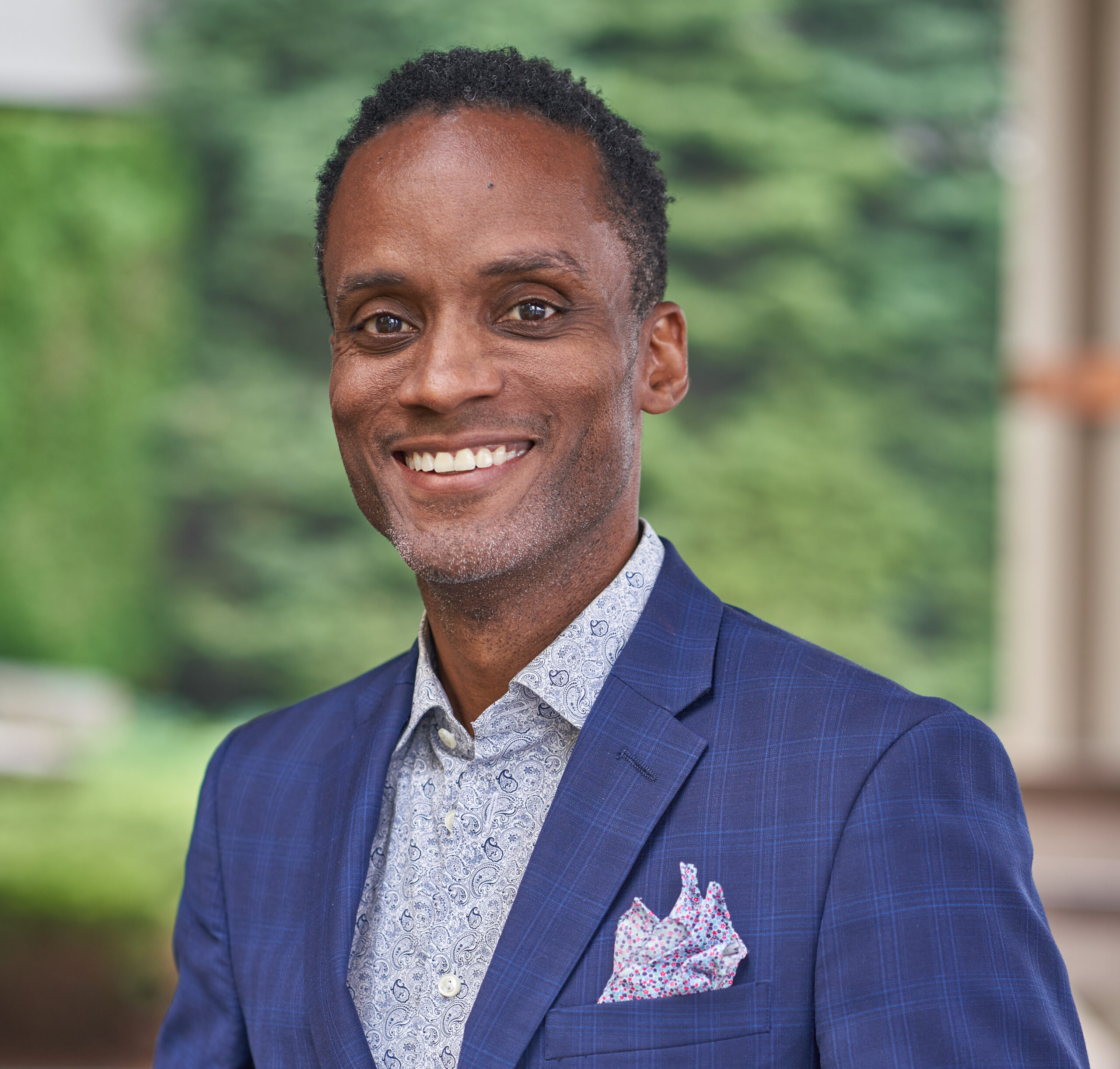 Headshot of a smiling man in a blue suit.