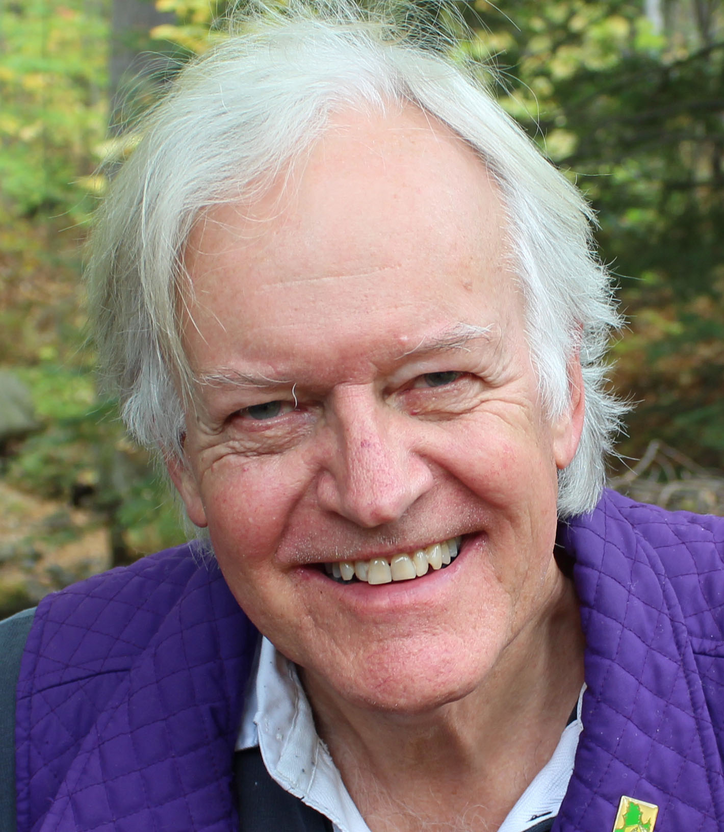 A headshot of a man in front of trees.