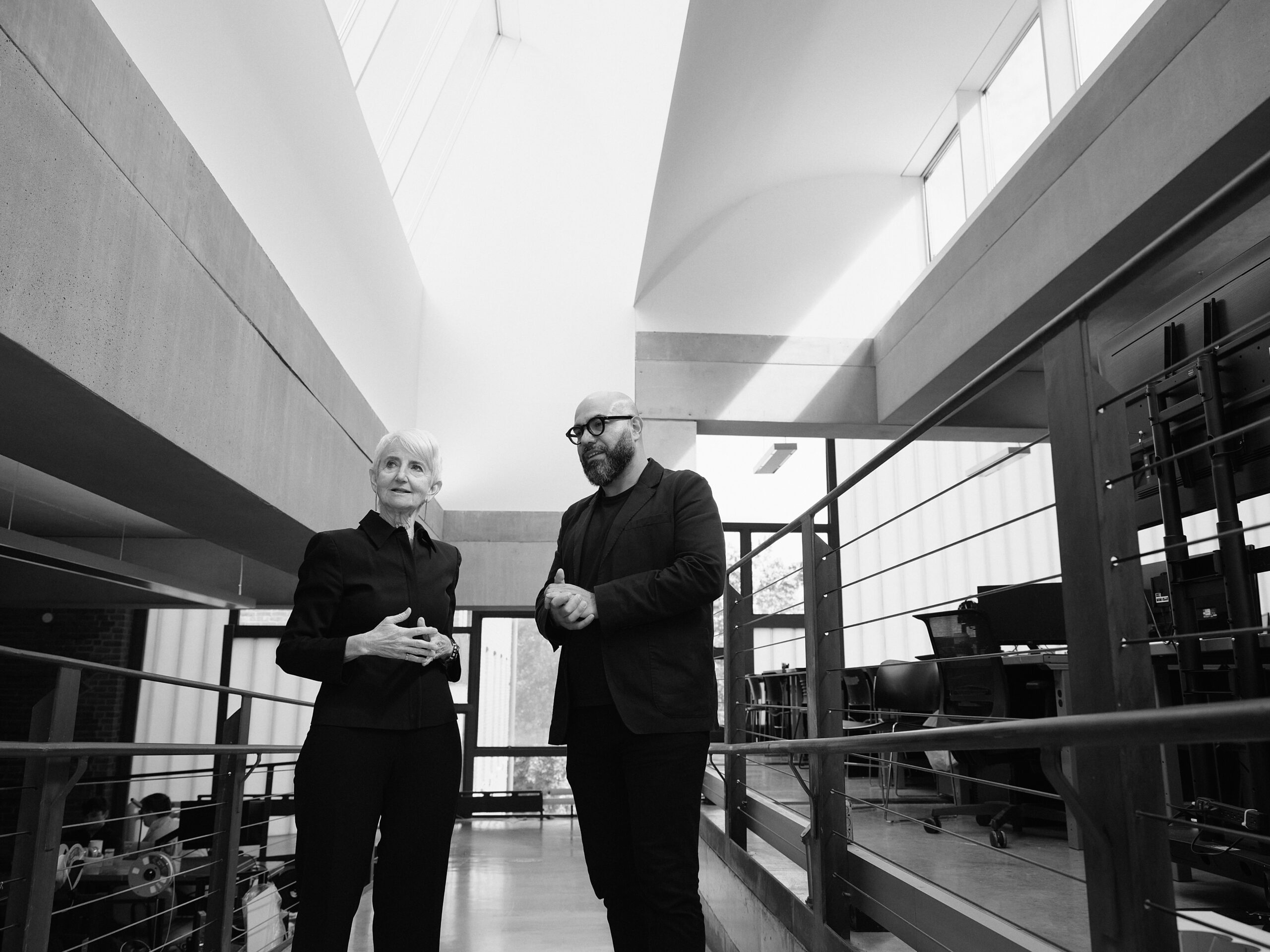 Pratt President Frances Bronet and Dean Quilian Riano talking to one another in a naturally lit hallway in Pratt’s Higgins Hall