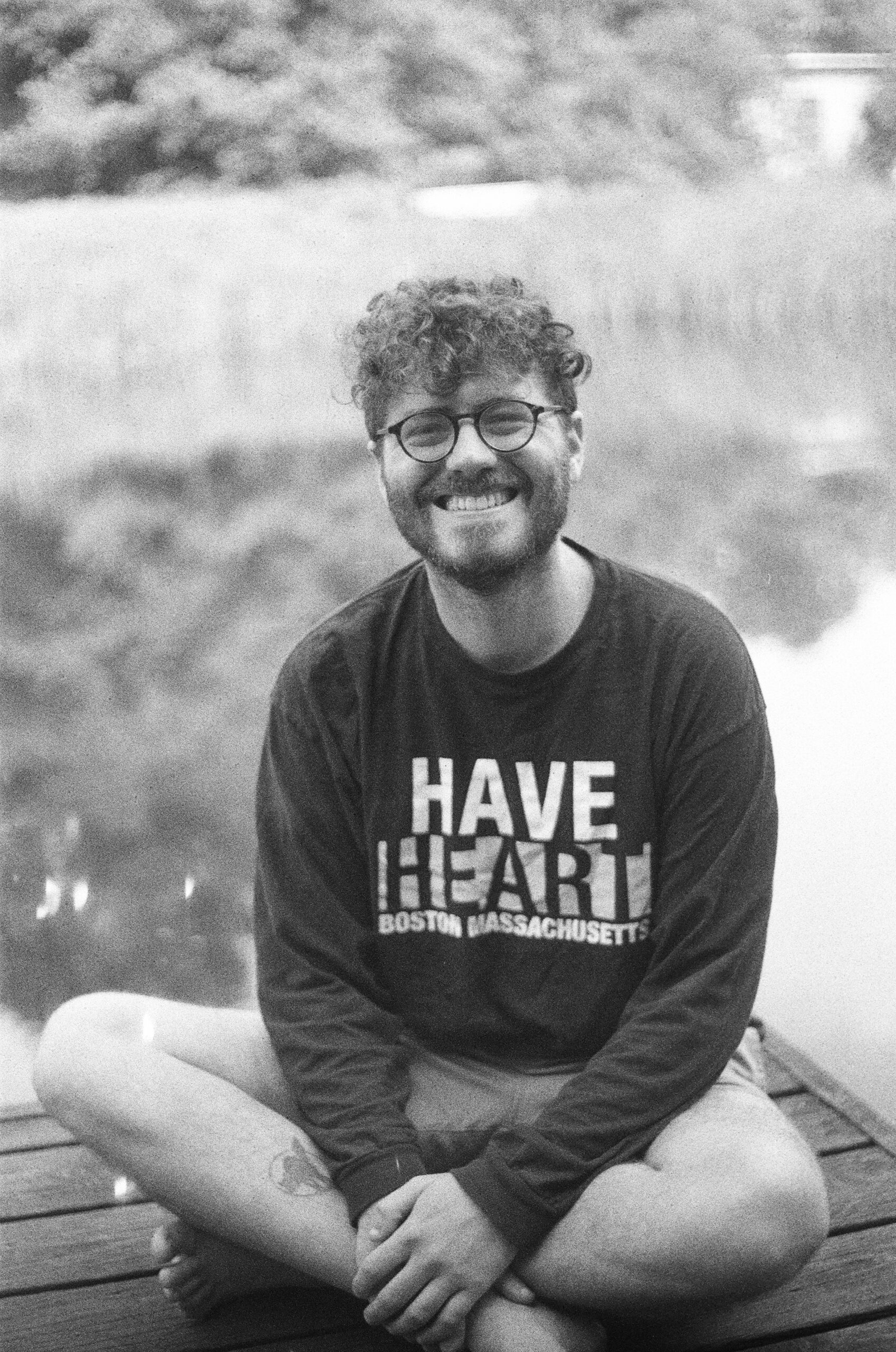 Smiling person seated cross-legged with T-shirt reading Have Heart