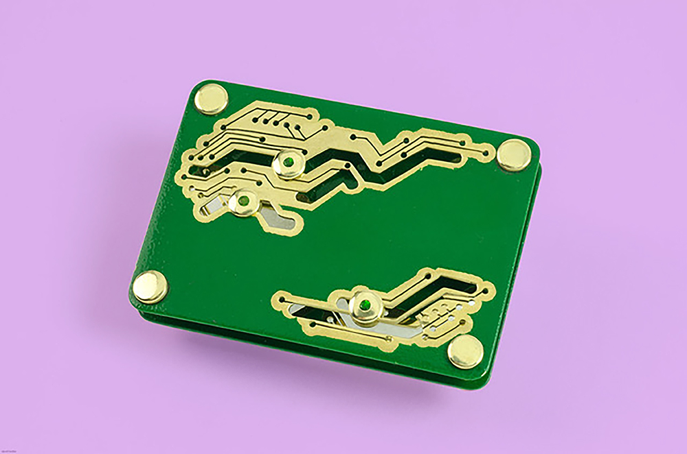 Image of a broch looking like a computer component, possibly a chip. It is placed on a purple background