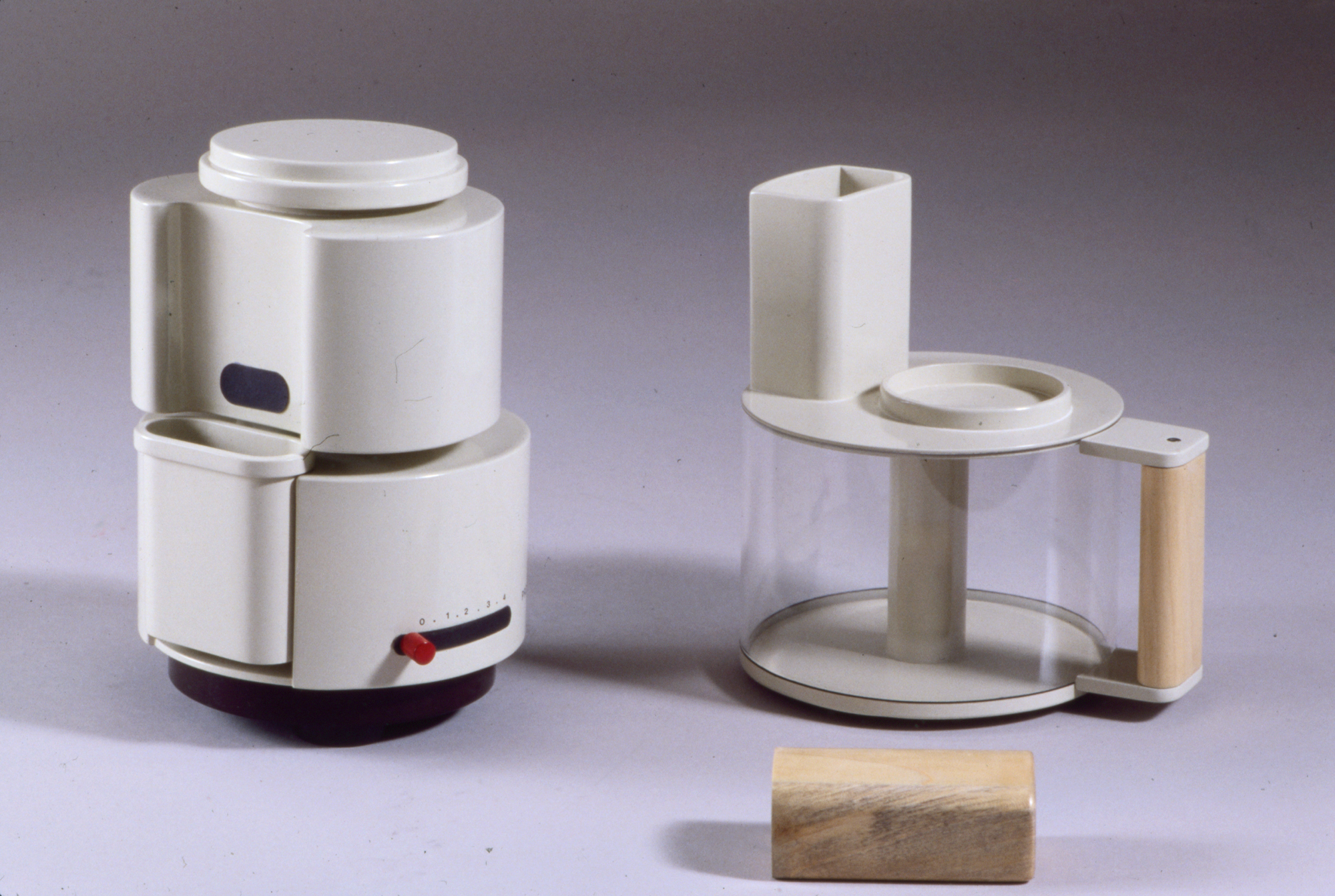 a white plastic kitchen machine with a clear pot and wooden handle, disassembled