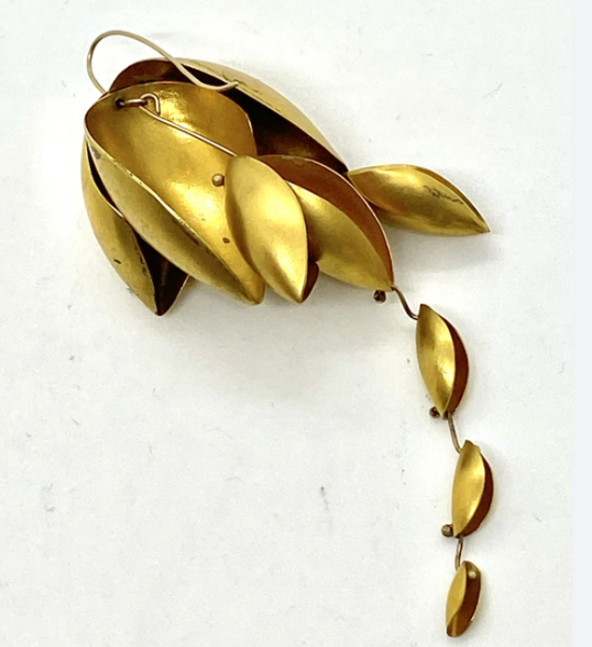 a gold earring in the shape of leaves