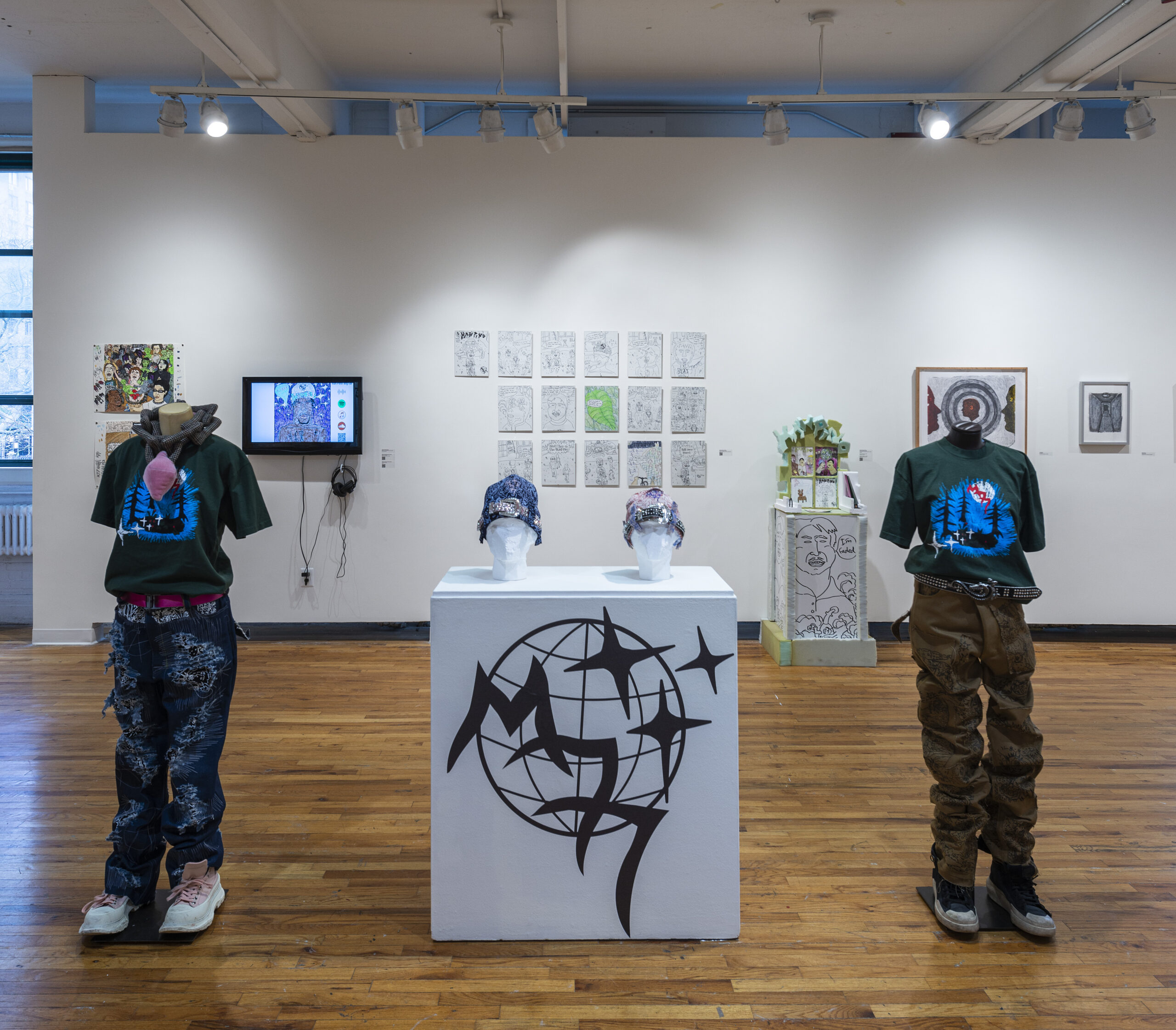 an exhibtion, with mannequins in foreground, monitor and artworks in background