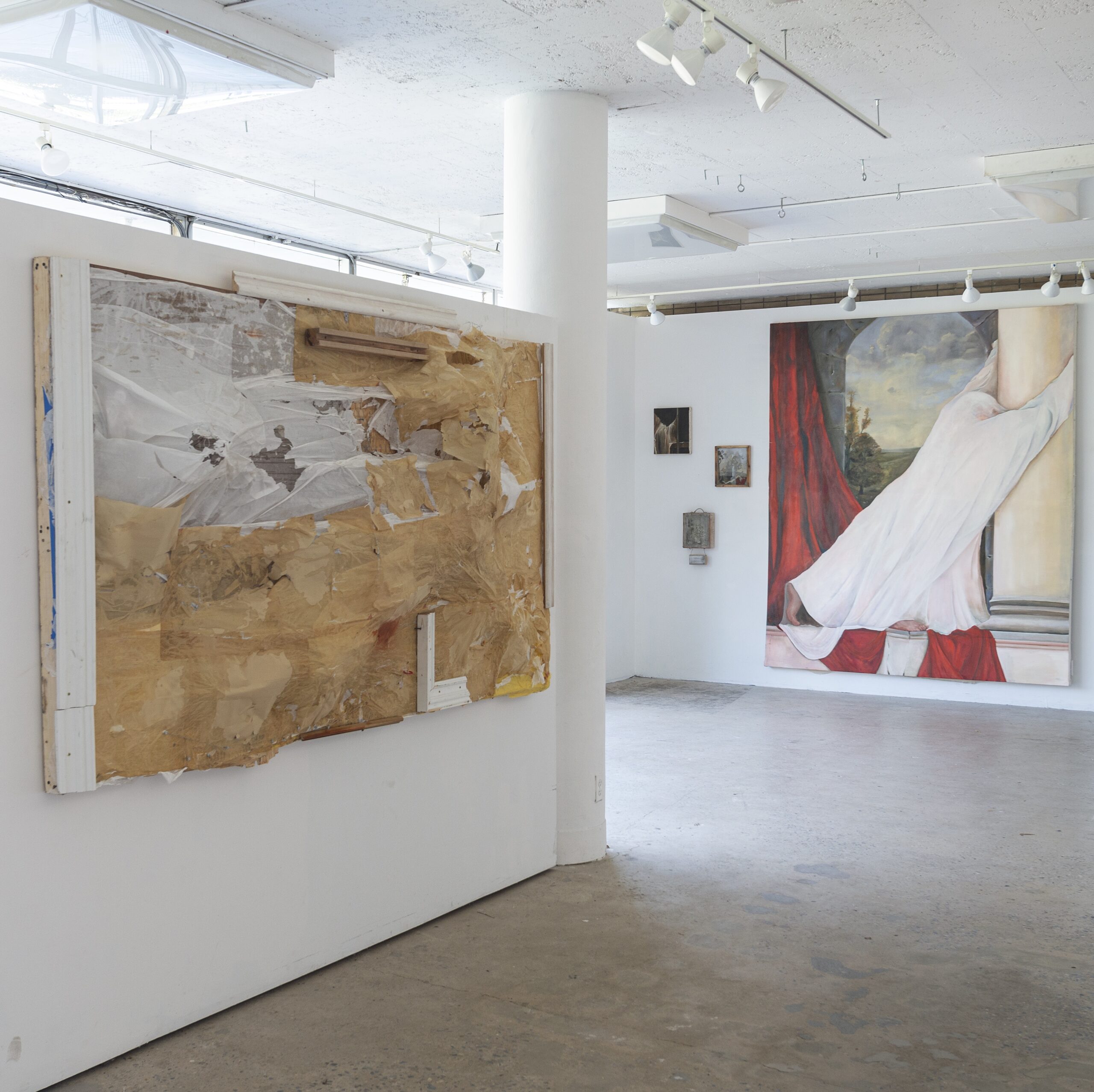 gallery room, with works hanging, perpendicular wall in background, with artworks hanging