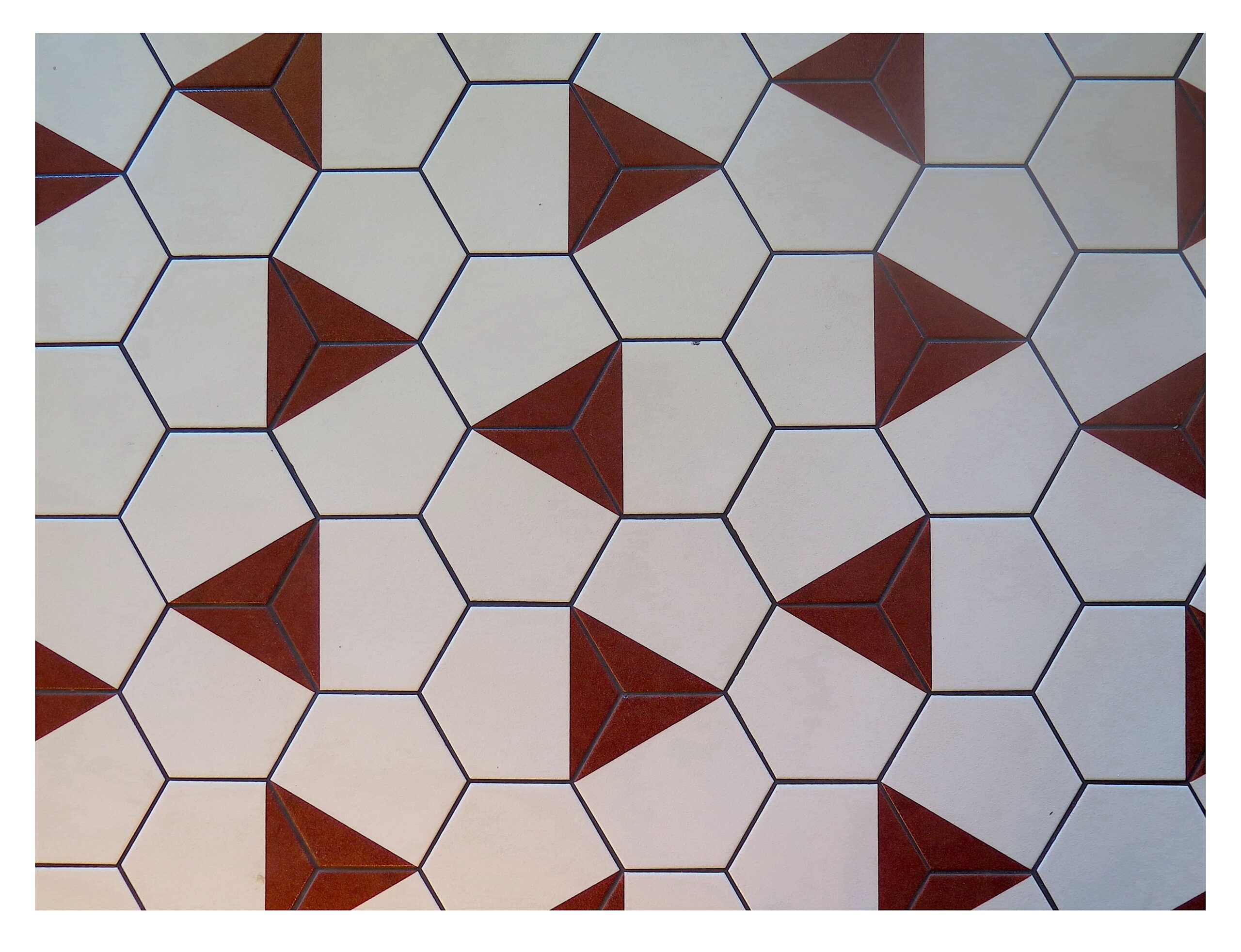 Floor Tile - Brian Brooks. Image of hexagon shaped white tiles with randomly painted red triangles.
