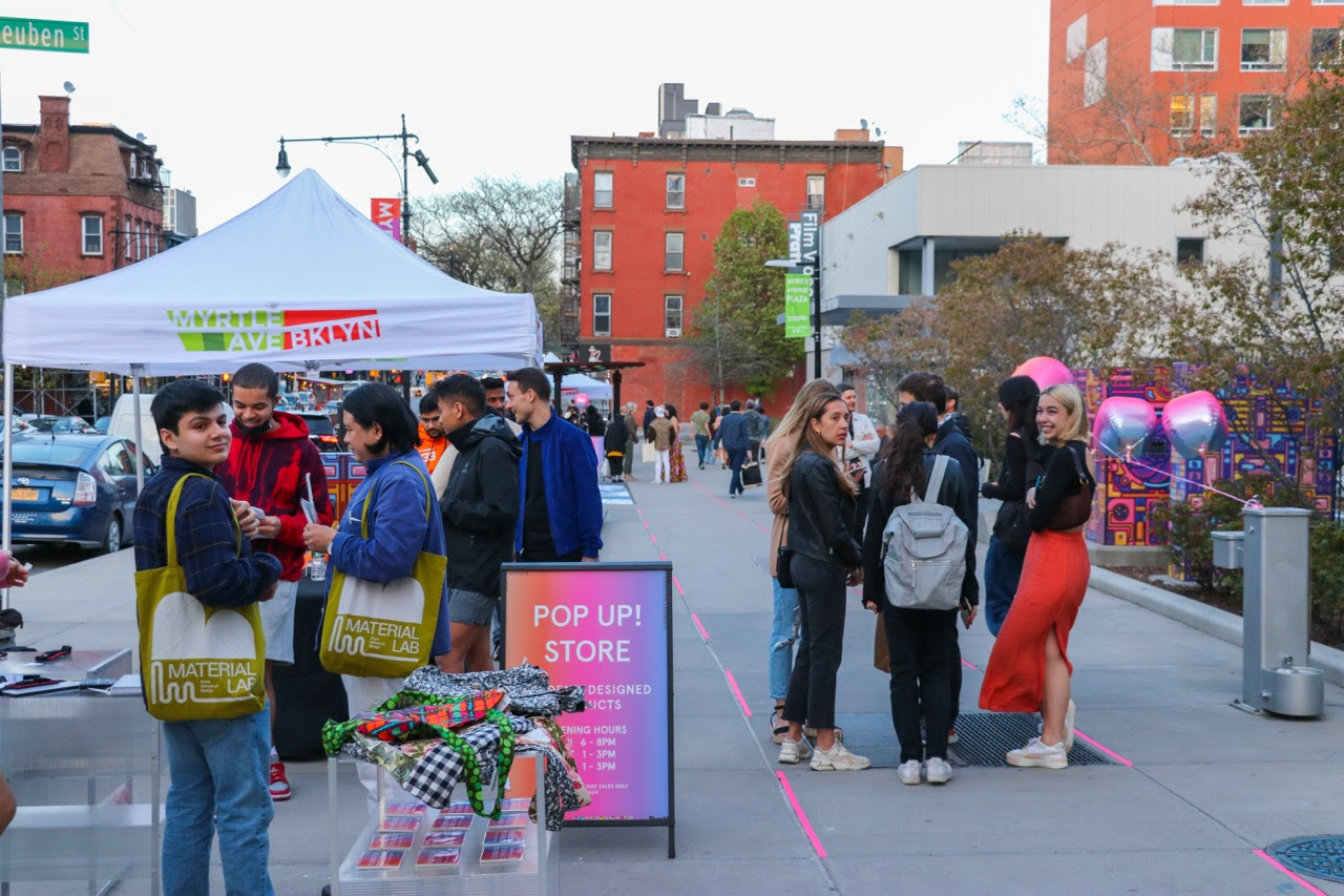 image of parking lot festival, people standing in foreground, booths in background