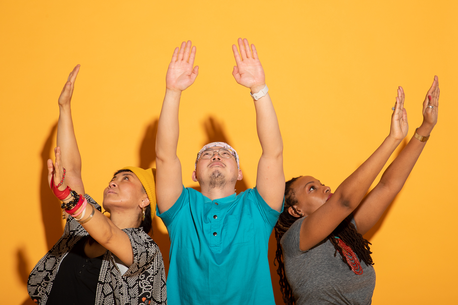 image of 3 people extending their arms towards the sky with their palms facing down.