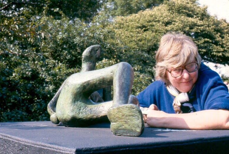 Woman poses with sculpture outdoors on a sunny day