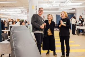 three people, standing to pose for a picture, smiling