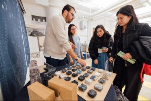 students and community members standing at a table, talking with each other