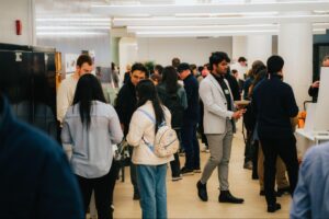 students and community members in a large room, talking with each other