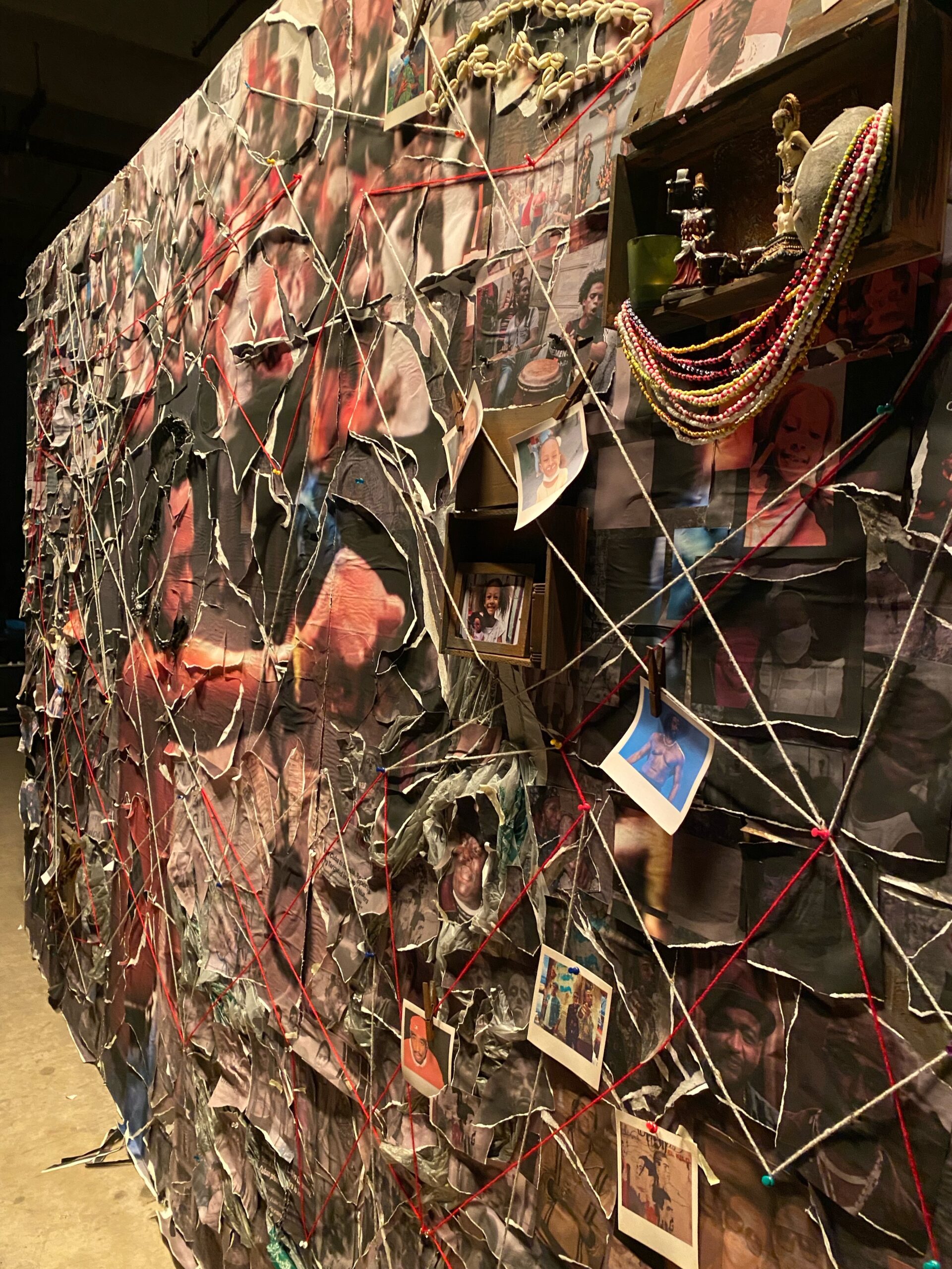 Mural of collaged torn news clippings, photos of prisons, and snapshots of people adhered to crumpled plastic, with a person in the center with a handcuffed fist out.