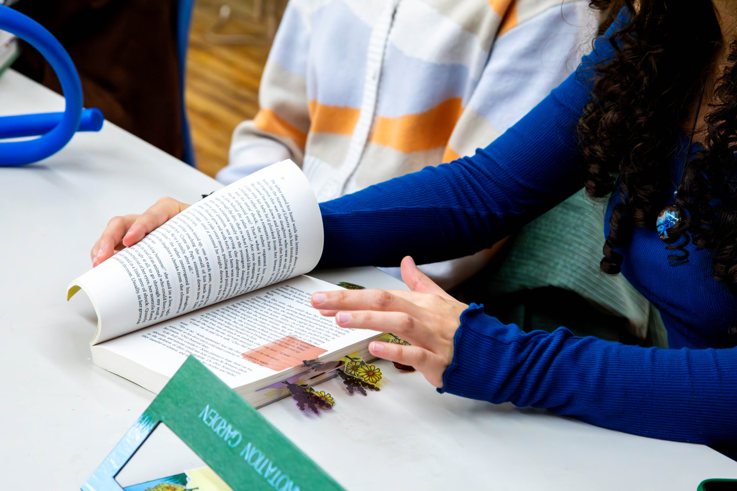 Hands turn pages of a book marked with playful bookmarks